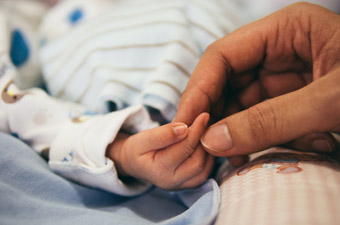 hand of newly-born bring caressed by hand hand of adylt female